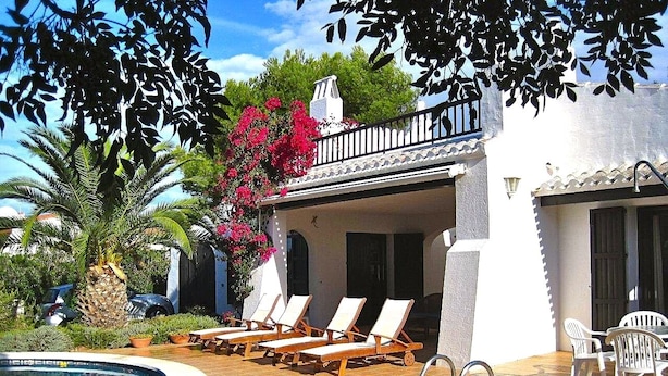 Un espace piscine avec des chaises longues, un palmier et un bâtiment doté d’un balcon.