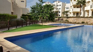 A swimming pool with a stone wall and a wooden fence. - Modern, accessible ground floor apartment just 30 minutes from Murcia airport (Corvera, Murcia)