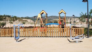 A playground with a wooden fence, swings, and climbing structures. - Modern, accessible ground floor apartment just 30 minutes from Murcia airport (Corvera, Murcia)
