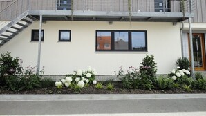 Un edificio de dos pisos con un balcón, una escalera y macetas con flores.
