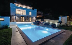 Enjoy a refreshing swim in the outdoor pool surrounded by a beautifully maintained lawn and stone pathway.