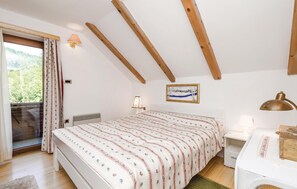A bedroom with a bed, a desk, a chair, a window with curtains, a painting, and a view of greenery outside. - Gorgeous home in Brod na Kupi with sauna (Brod na Kupi)