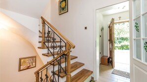 Eine Holztreppe mit schwarzen Stakobel und Zugang zum zweiten Stock.