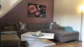 A modern living room with a sectional sofa, a white coffee table, and a painting of flowers on the wall. - Apartment Lichtblick near Centro  (Oberhausen)