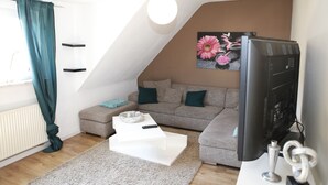 A modern living room with a grey sofa, a white coffee table, and a flat-screen TV. - Apartment Lichtblick near Centro  (Oberhausen)