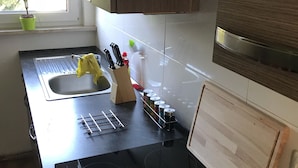A modern kitchen with a black countertop, stainless steel sink, and wooden cabinets. - Apartment Lichtblick near Centro  (Oberhausen)