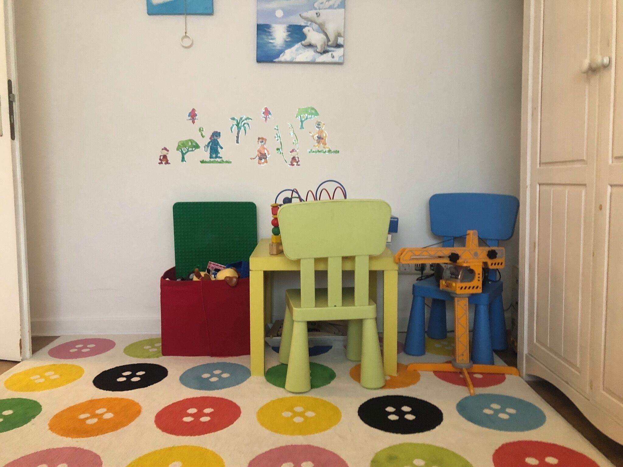 Ein Spielbereich für Kinder mit bunten Stühlen, einem kleinen Tisch und einer Spielkonstruktion.