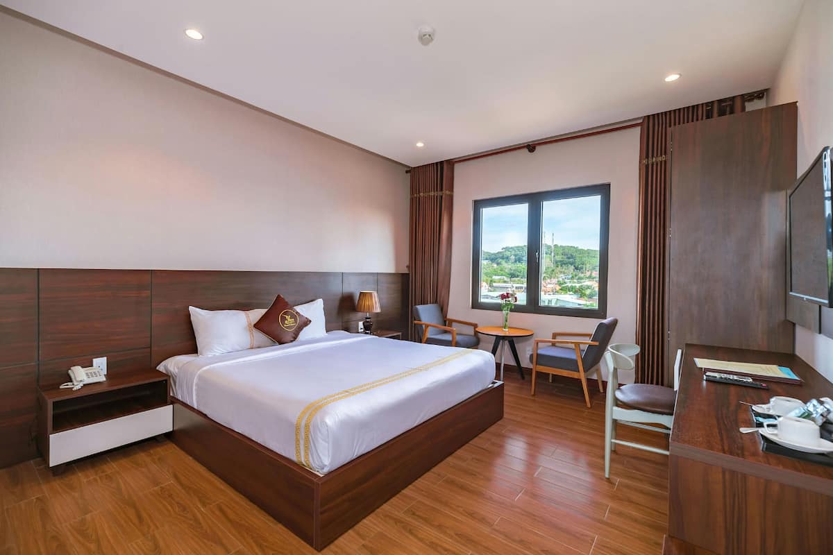 A modern hotel room with a large bed, a desk, and a view of the outdoors.