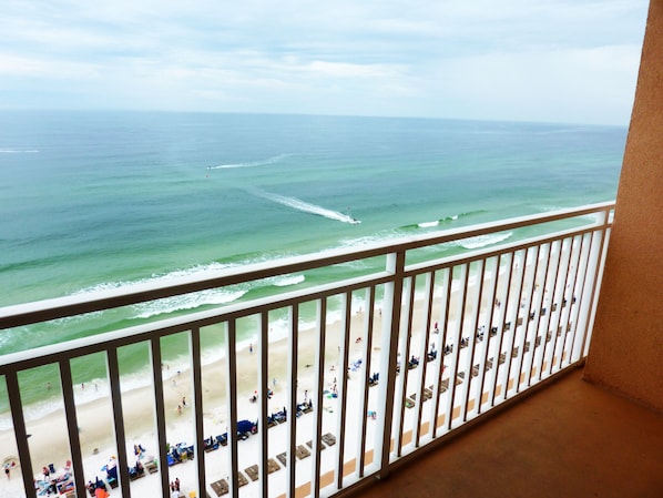 A balcony with a view of the beach and ocean.