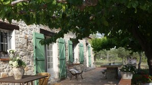 A stone building with green shutters, wicker furniture, and potted plants. - PROVENCE MAS OF ATYPICAL CHARACTERS (Draguignan)