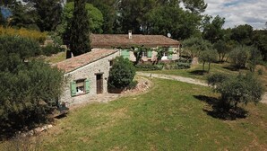 Una casa in pietra con tetto in tegole, circondata da alberi e da un'area verde.