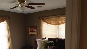A bedroom with a bed, a ceiling fan, and a window with blinds.
