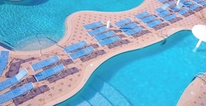 An aerial view of Majestic Beach Resort with a large pool, sun loungers, and a beach area.