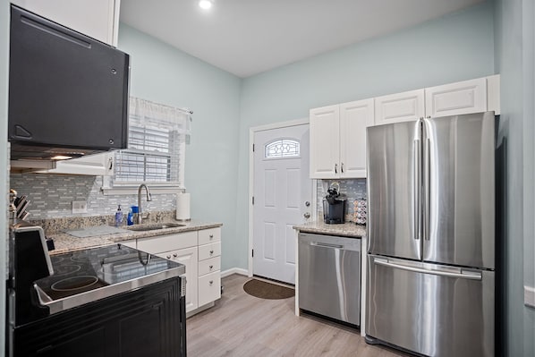 A modern kitchen with white cabinetry, stainless steel appliances, and a granite countertop.