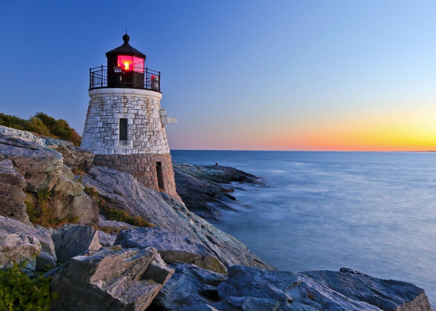 Un faro sobre una costa rocosa al atardecer.