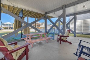 Un espace extérieur abrité, équipé de tables et de chaises pour pique-niquer, d’un panier de basketball et offrant une vue sur les bâtiments environnants.