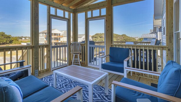 Une terrasse couverte avec des rampes en bois, une table et des sièges bleus.