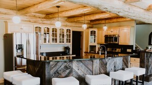 Una cocina con armarios de madera, una isla de mármol y taburetes de bar.