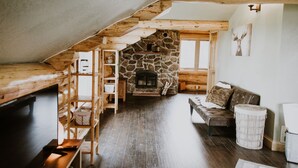 Un dormitorio estilo loft acogedor, con chimenea de piedra, vigas de madera y una estética rústica.