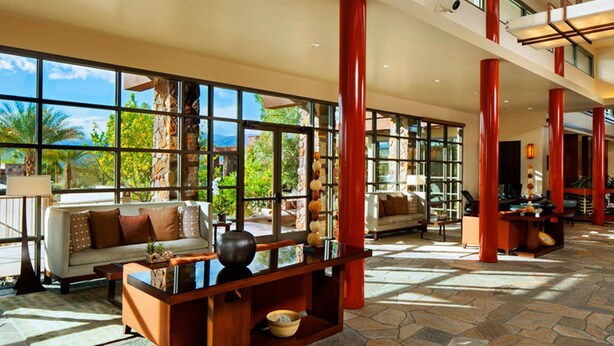 A spacious lobby with large windows, a stone floor, and a modern seating area.