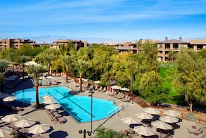 Un resort con piscina circondata da palme e lettini.
