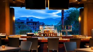 An outdoor bar area with wicker chairs and a bar stocked with various bottles.