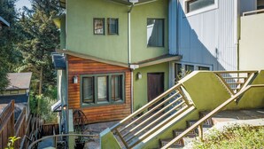 A multi-level house with a wooden deck, a staircase, and a small garden area.