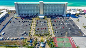 Ein großes Hotel mit einem zentralen Turm, großzügigem Parkplatz und Blick auf den Strand.