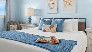 Ein Schlafzimmer mit einem Bett, blauer Bettwäsche, einem Frühstücksbrett und Wandbildern.