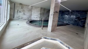 Ein modernes Badezimmer mit Marmorboden, einer zentral platzierten Badewanne und einem großen Fenster.