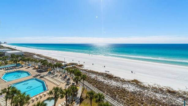 Ein Strandresort mit Poolbereich, Zugang zum Strand und strahlend blauem Himmel.