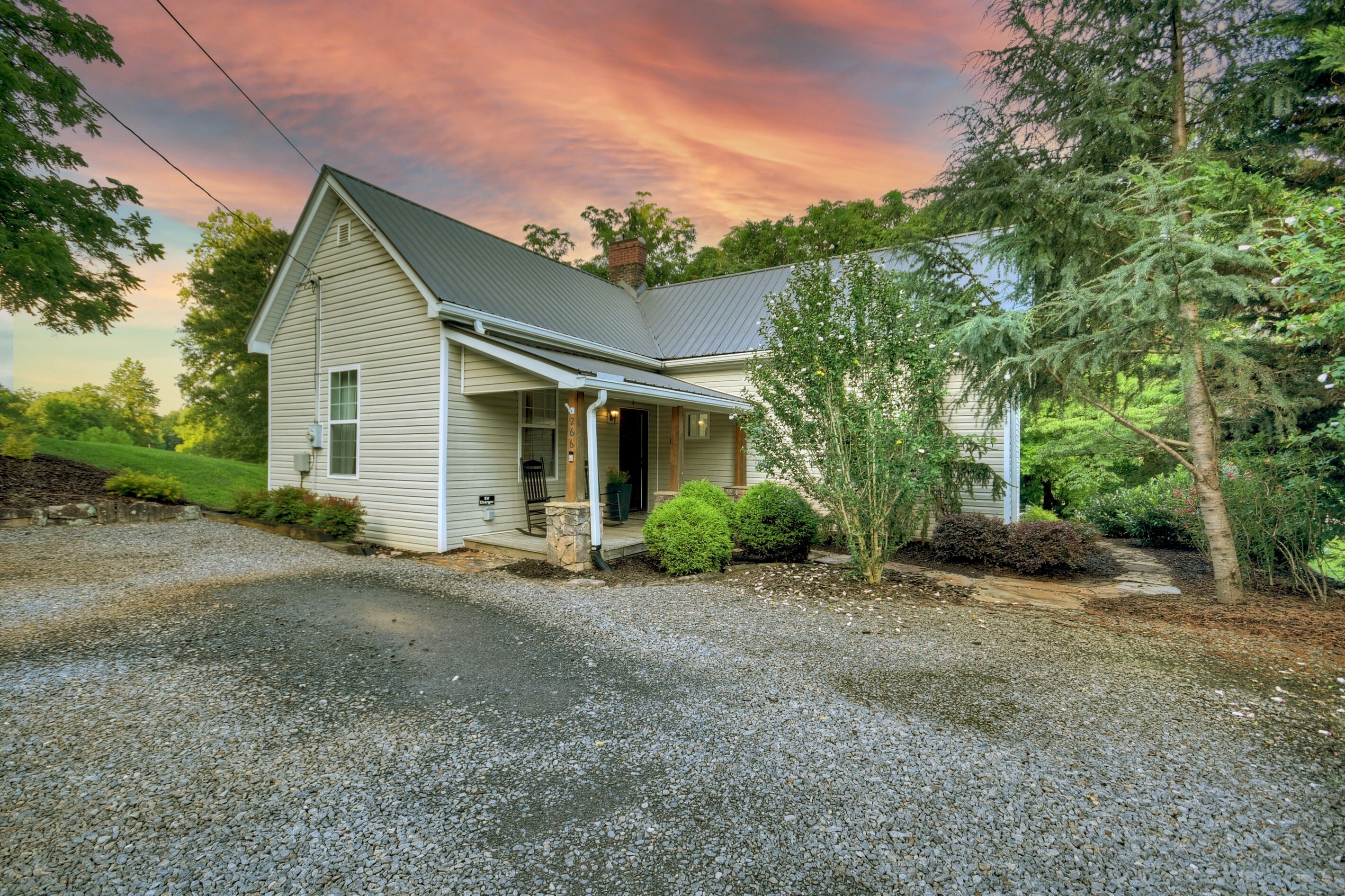 A single-story house with a gabled roof, a front porch, and a gravel driveway.