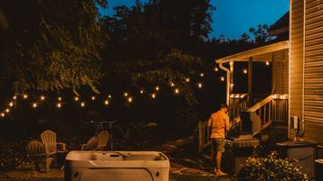 A backyard with a hot tub, string lights, and outdoor seating.