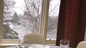 Une table à manger recouverte d’une nappe à motifs, avec une assiette et plusieurs verres.