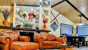 Una sala de estar acogedora con sofás de cuero, una chimenea de piedra y un techo rústico.