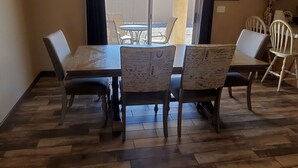 A dining area with a wooden table and chairs, a view of the outdoors through a window, and a tiled floor. - snowbirds email of call for winter pricing<br>951-741-7590 occapt@hotmail.com (Lake Havasu City)