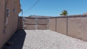 A fenced outdoor area with a gravel surface, a metal gate, and a building on one side. - snowbirds email of call for winter pricing<br>951-741-7590 occapt@hotmail.com (Lake Havasu City)