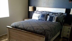A bedroom with a wooden bed, a nightstand, a bedside table, and a small round table. - snowbirds email of call for winter pricing<br>951-741-7590 occapt@hotmail.com (Lake Havasu City)