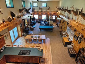 A spacious living area with a pool table, wooden furniture, and mounted animal heads on the walls. - MCR  is a property that features seclusion and privacy that is hard to find.  (Rushford)