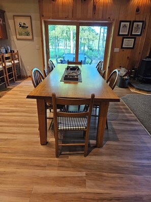 A wooden dining table with chairs, framed artwork on the walls, and a view of trees through the window. - MCR  is a property that features seclusion and privacy that is hard to find.  (Rushford)