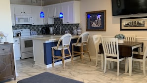 Une cuisine moderne avec des meubles blancs, un îlot central et un coin repas avec des chaises blanches.