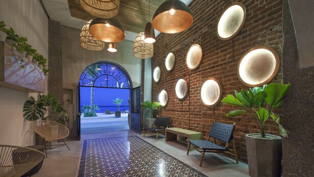 A modern lobby with a patterned floor, seating area, and a brick wall with circular mirrors.
