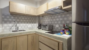 A kitchen with wooden cabinets, a stainless steel refrigerator, a microwave, and a coffee maker.