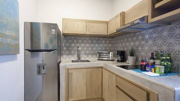 A modern kitchen with a stainless steel refrigerator, wooden cabinets, a patterned backsplash, and a countertop with various items.