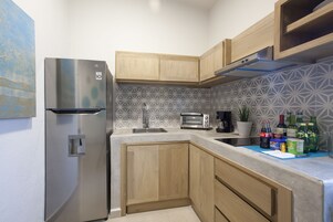 A modern kitchen with a stainless steel refrigerator, wooden cabinets, a patterned backsplash, and a countertop with various items.