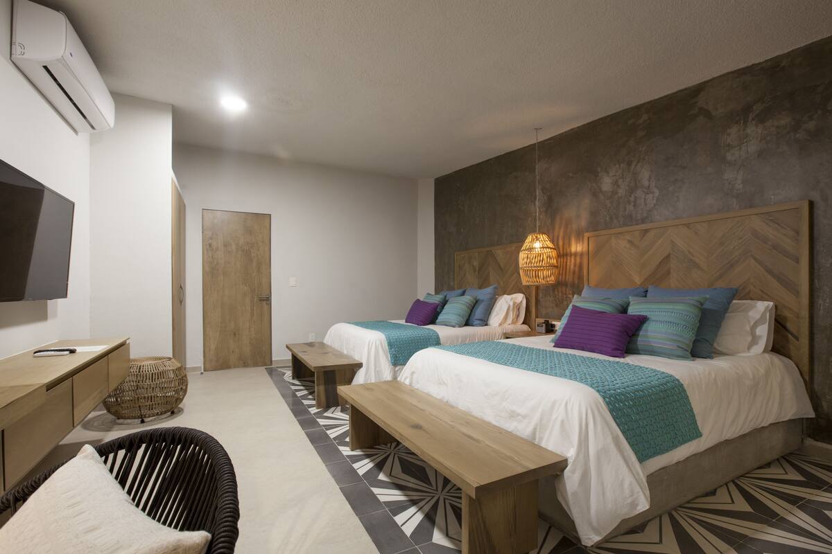 A modern hotel room with two beds, a desk, a chair, and a television.