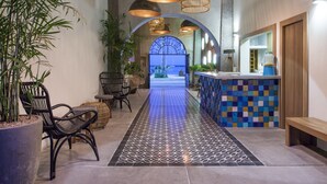 A lobby with a tiled floor, wicker chairs, a reception desk, and hanging wicker lamps.
