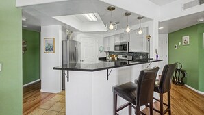 A modern kitchen with a central island, bar stools, and pendant lighting. - Dessert Oasis - 2BR Desert Breeze Retreat with Pool - jacuzzi- Gym (Phoenix)