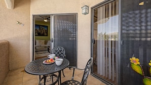 A patio with a table, chairs, and a sliding glass door. - Dessert Oasis - 2BR Desert Breeze Retreat with Pool - jacuzzi- Gym (Phoenix)