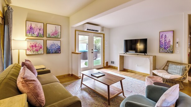 Un salon comprenant un canapé, un fauteuil, une table basse et des œuvres d’art accrochées aux murs.